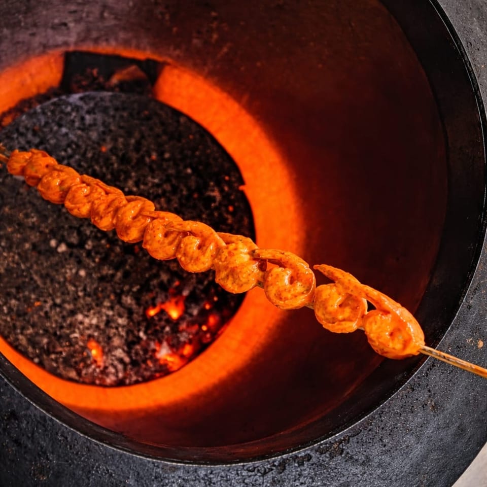 Marinated shrimp skewers cooking inside a glowing hot tandoor oven with embers.
