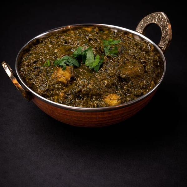 Palak Paneer, a vibrant green Indian spinach and cheese curry, in a copper serving bowl.